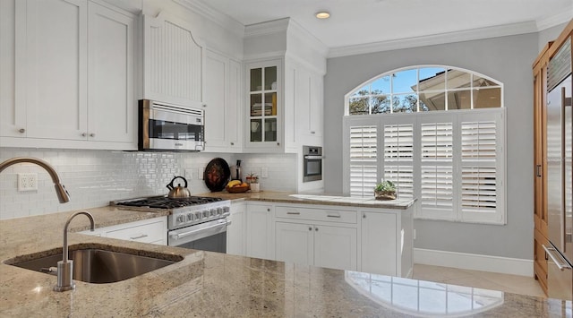 kitchen featuring appliances with stainless steel finishes, light stone counters, a sink, crown molding, and backsplash