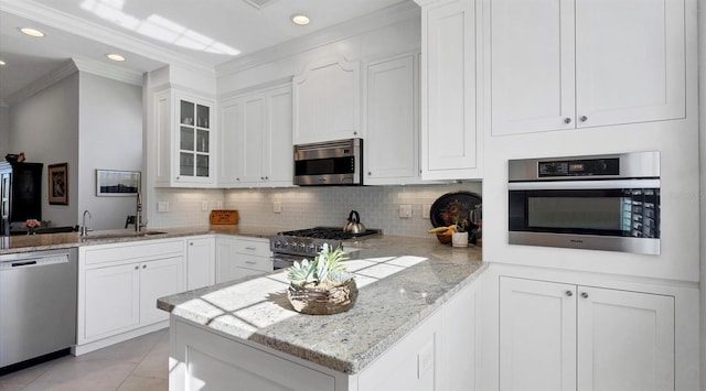 kitchen with stainless steel appliances, a peninsula, a sink, and white cabinetry