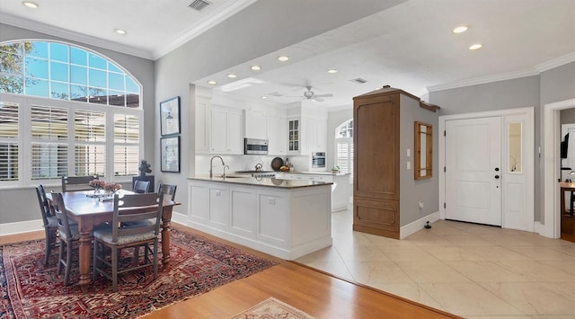 kitchen with baseboards, white cabinetry, stainless steel microwave, and crown molding