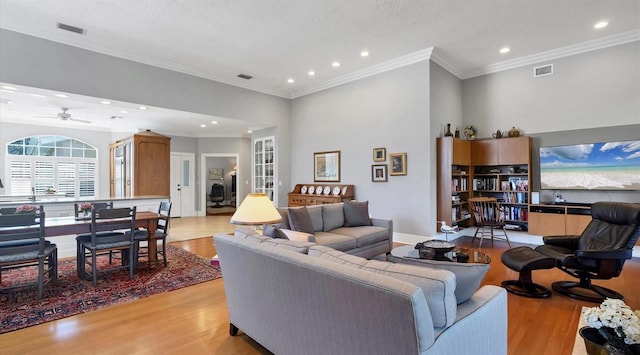 living area with light wood-style floors, recessed lighting, visible vents, and crown molding