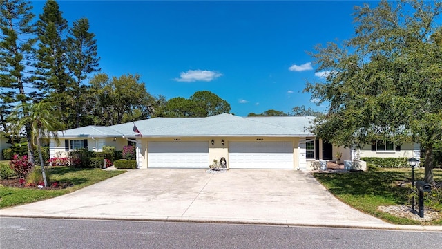 ranch-style home featuring a garage, concrete driveway, a front yard, and stucco siding