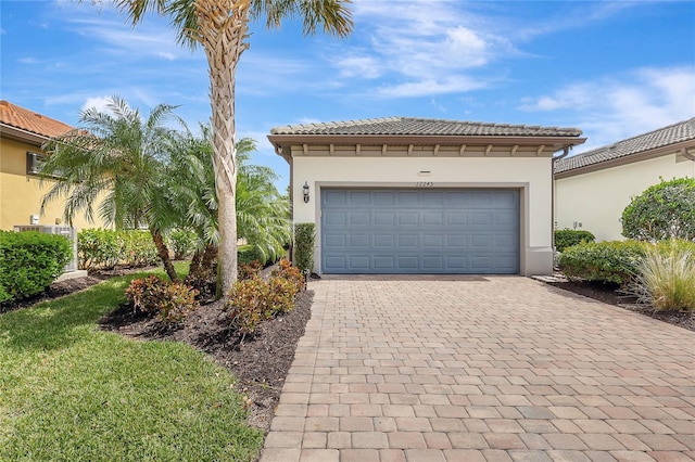 view of front of home featuring a tiled roof, decorative driveway, an attached garage, and stucco siding