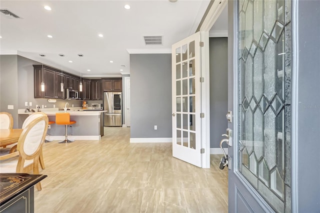 kitchen with appliances with stainless steel finishes, visible vents, ornamental molding, and dark brown cabinets