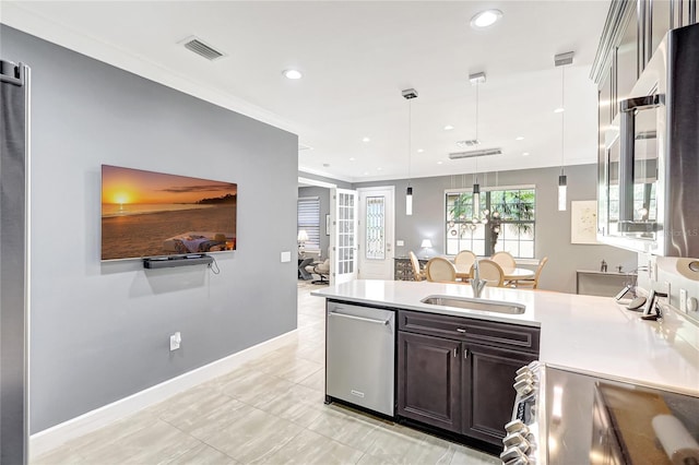 kitchen featuring dark brown cabinetry, a sink, light countertops, appliances with stainless steel finishes, and decorative light fixtures