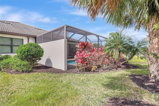 view of yard featuring a garage, glass enclosure, and an outdoor pool