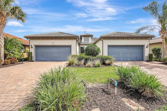 view of front of house with an attached garage, stucco siding, decorative driveway, and a tiled roof