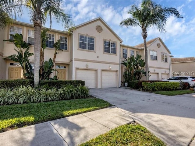 multi unit property featuring concrete driveway, an attached garage, and stucco siding