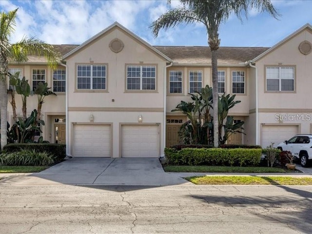 multi unit property featuring driveway, an attached garage, and stucco siding