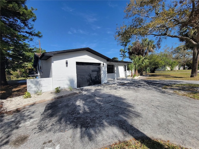 view of side of home featuring an attached garage and aphalt driveway