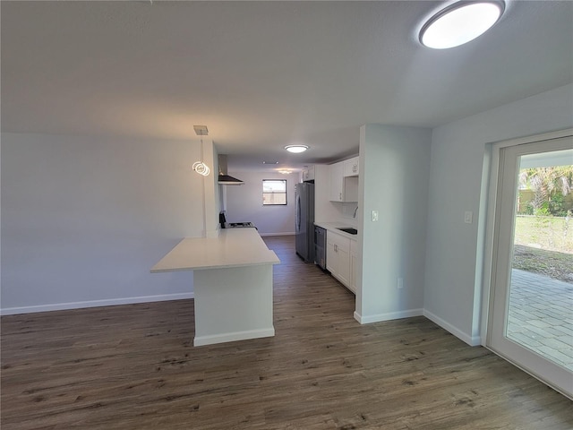 kitchen featuring appliances with stainless steel finishes, a wealth of natural light, dark wood finished floors, and wall chimney exhaust hood