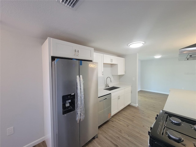 kitchen featuring stainless steel appliances, a sink, light countertops, and white cabinetry