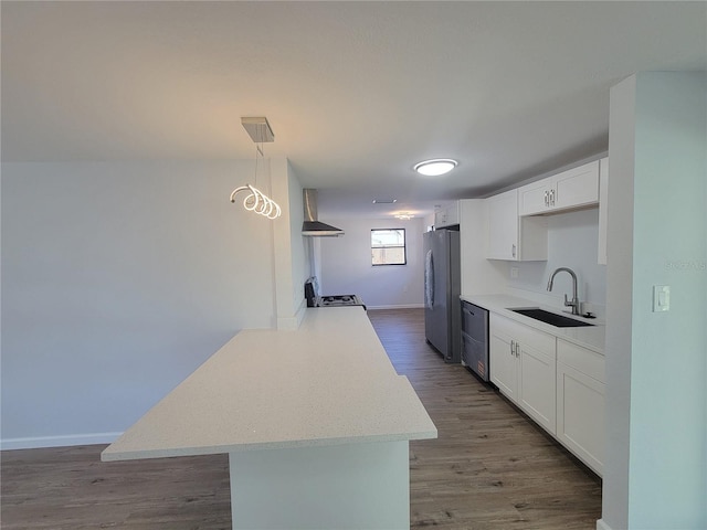 kitchen featuring stainless steel appliances, wood finished floors, a sink, white cabinets, and wall chimney range hood