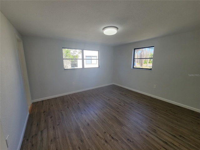 unfurnished room featuring dark wood-style floors, baseboards, and a textured ceiling