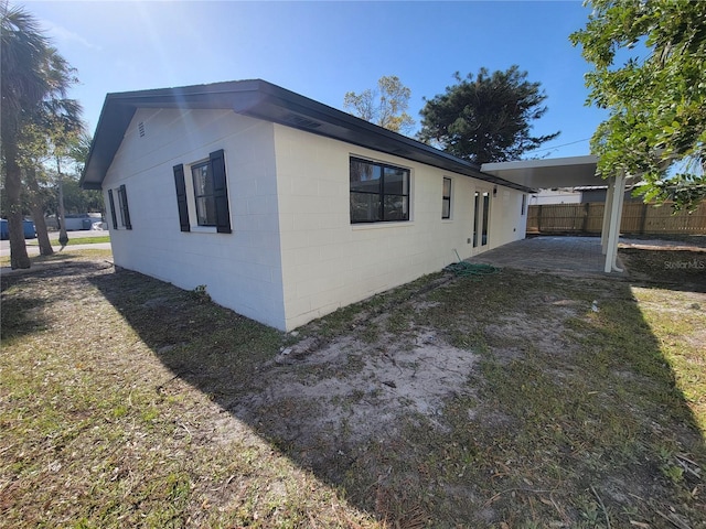 view of property exterior featuring a patio area, concrete block siding, and fence