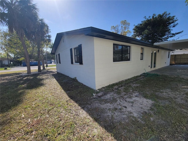 view of home's exterior with fence and concrete block siding