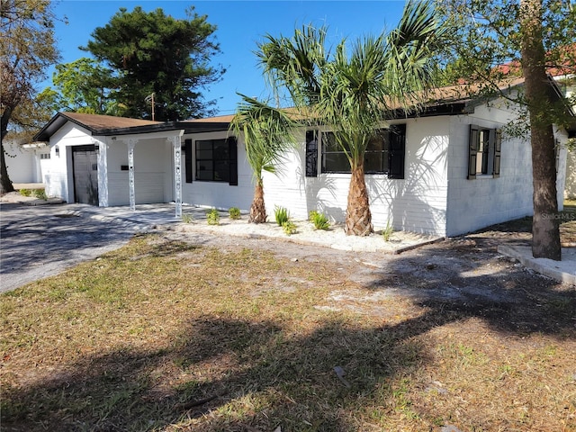 view of front of home featuring driveway, an attached garage, and concrete block siding