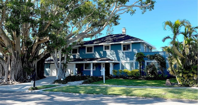 view of front of property with driveway, a garage, a chimney, and a front lawn