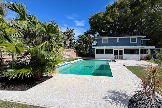 outdoor pool featuring a patio area, fence, and a sunroom