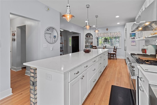 kitchen with light countertops, high end stainless steel range oven, white cabinetry, light wood-type flooring, and extractor fan