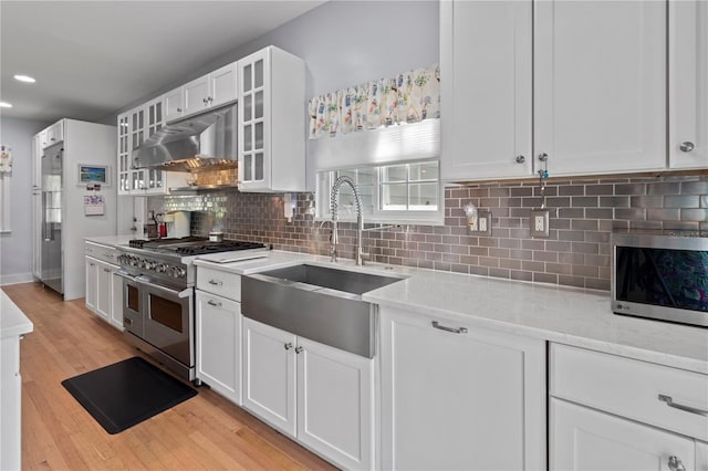 kitchen with white cabinets, a sink, under cabinet range hood, and high quality appliances