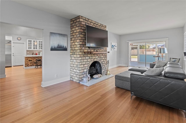 living room with a fireplace, wood finished floors, and baseboards