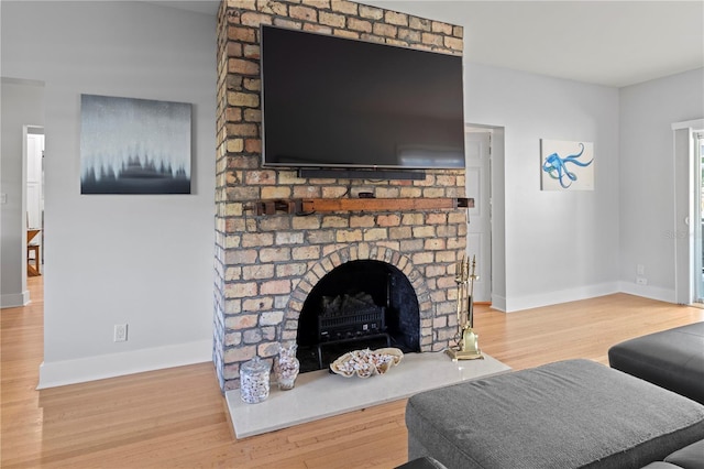 living area with a fireplace, baseboards, and wood finished floors