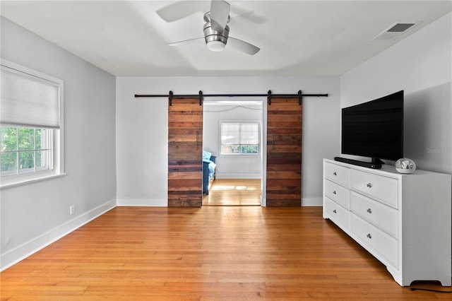 bedroom featuring visible vents, light wood finished floors, and a barn door