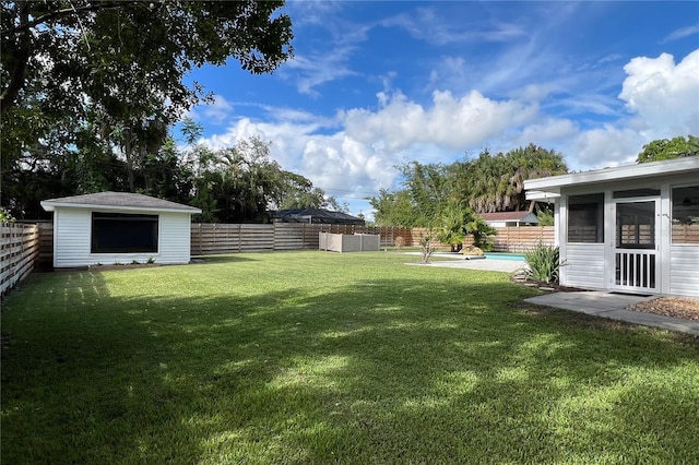 view of yard featuring a sunroom, a fenced backyard, an outdoor structure, and a storage shed