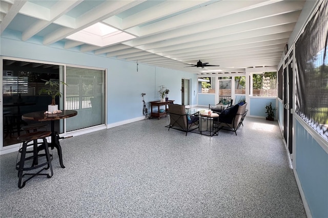 sunroom / solarium with a skylight, ceiling fan, and beam ceiling