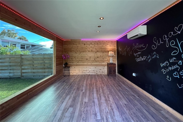 spare room featuring an AC wall unit, recessed lighting, wood finished floors, and wooden walls