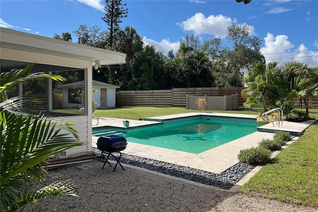 view of pool featuring a fenced in pool, a fenced backyard, an outbuilding, a yard, and a patio area