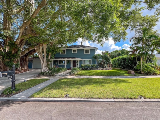 traditional style home featuring a garage, driveway, and a front lawn