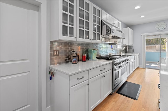 7735 Westmoreland Dr, Sarasota, FL 34243 - kitchen with double oven range, under cabinet range hood, backsplash, light wood-style flooring, and glass insert cabinets