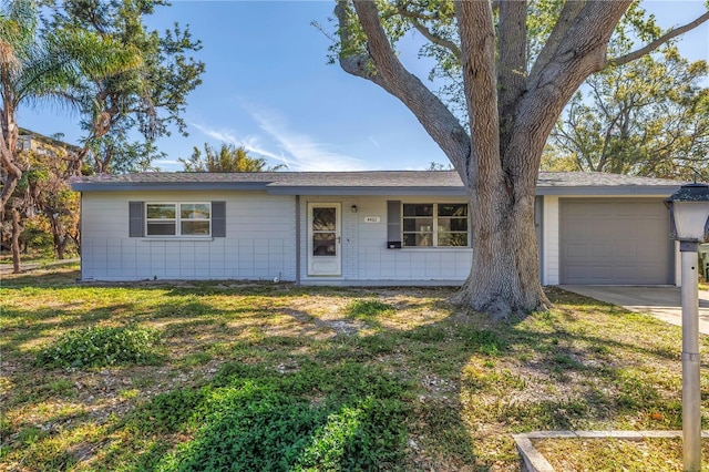 ranch-style home with concrete driveway, a garage, and a front lawn