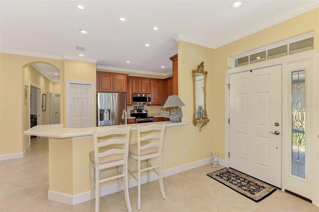 kitchen with arched walkways, a peninsula, visible vents, appliances with stainless steel finishes, and ornamental molding