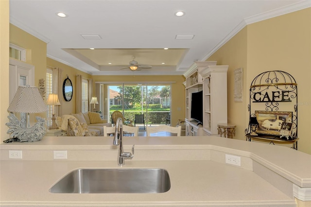 kitchen with recessed lighting, a sink, open floor plan, light countertops, and ornamental molding