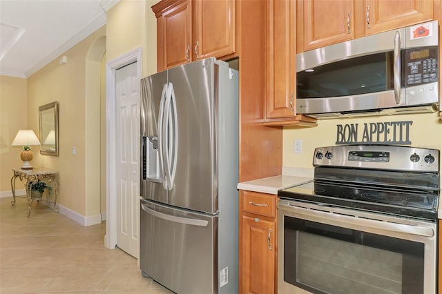 kitchen with light tile patterned floors, baseboards, appliances with stainless steel finishes, light countertops, and crown molding