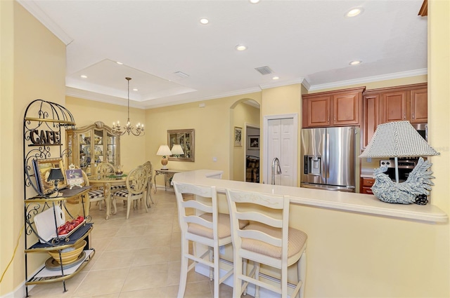 kitchen featuring light tile patterned flooring, ornamental molding, arched walkways, and stainless steel fridge with ice dispenser