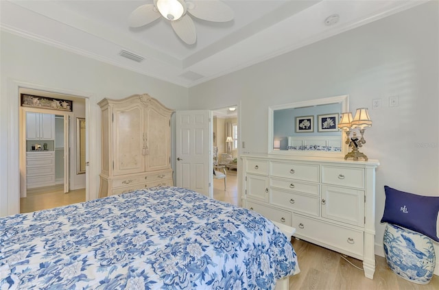 bedroom with light wood-style flooring, visible vents, a ceiling fan, ornamental molding, and a tray ceiling