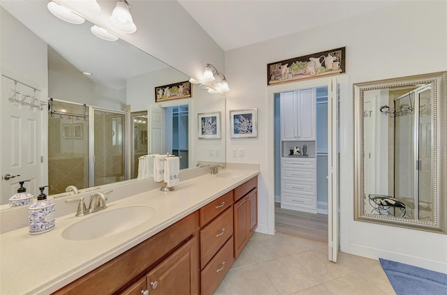 full bath with double vanity, a stall shower, a sink, and tile patterned floors