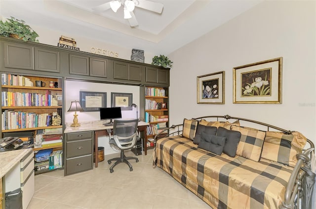 home office featuring a ceiling fan, a tray ceiling, and light tile patterned flooring