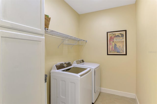 laundry room with light tile patterned floors, laundry area, washing machine and dryer, and baseboards