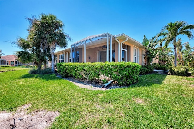 view of side of property featuring a lawn, a lanai, and stucco siding