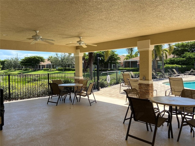 view of patio / terrace with a ceiling fan, outdoor dining space, fence, and a community pool