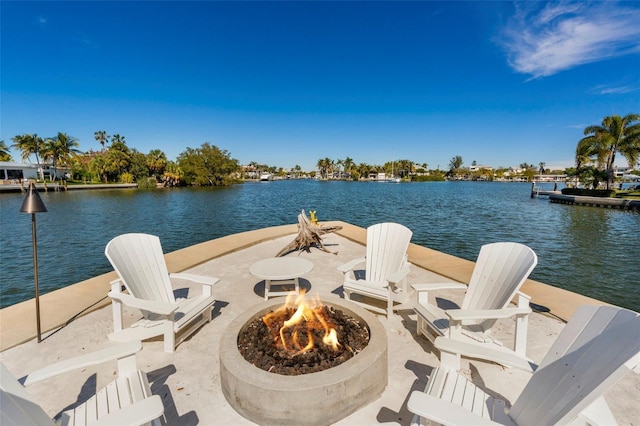 view of patio featuring an outdoor fire pit, a water view, and a dock