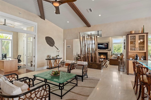 living room with vaulted ceiling with beams, a lit fireplace, visible vents, and ceiling fan