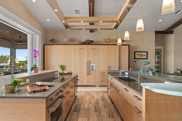 kitchen featuring modern cabinets, light brown cabinets, stainless steel oven, and a sink