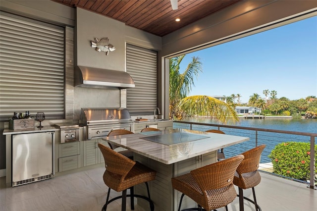 view of patio featuring a water view, an outdoor kitchen, a grill, a sink, and outdoor wet bar