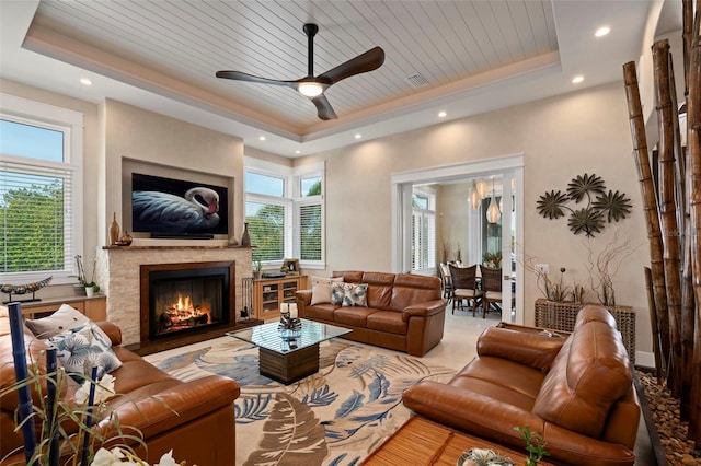 living room featuring wooden ceiling, a warm lit fireplace, visible vents, and a raised ceiling