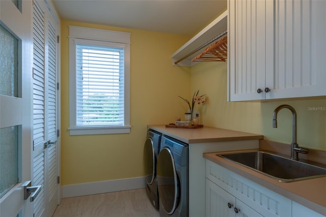 laundry area with washer and dryer, cabinet space, a sink, and baseboards